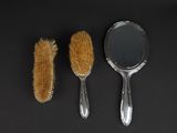 two brushes and a mirror on a black surface