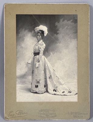 an old photo of a woman in a dress and hat