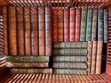 de nombreux livres anciens empilés sur une étagère dans une bibliothèque