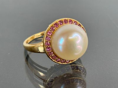 an image of a pearl and pink sapphire ring on a reflective surface