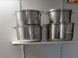 des casseroles et des poêles sont posées sur une étagère dans une cuisine