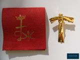 une croix en or sur un tissu rouge, à côté d'un crucifix en or