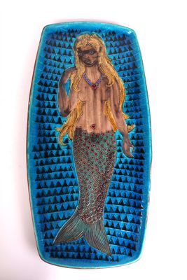 blue and green plate with a mermaid holding a fish on it ' s back
