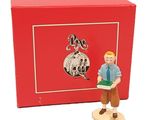 une figurine représentant un homme tenant un livre devant une boîte rouge