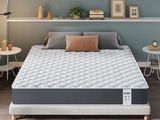une photo d'un matelas dans une chambre à coucher, avec une fenêtre en arrière-plan
