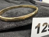 un bracelet en or posé sur un morceau de tissu, avec une étiquette de prix