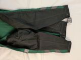 a pair of black and green pants laying on a bed