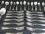 many silver spoons and forks laid out on a table