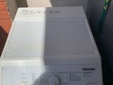 white washer sitting on top of a washing machine in front of a brick wall