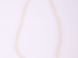 un collier de perles blanches avec un fermoir en argent sur fond blanc