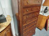a tall wooden chest of drawers with a lamp on top of it
