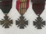 three medals and a cross are sitting on a white surface