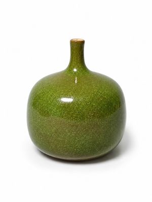 un vase vert posé sur une surface blanche
