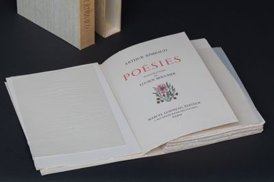 un livre ouvert sur une table, à côté d'une pile de livres
