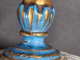 a close up of a blue and gold vase on a table