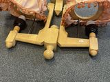 pair of wooden dolls with bonnets on wheels on a carpeted floor