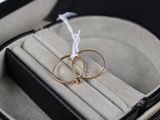 deux bagues en or dans un écrin noir, attachées par un cordon blanc