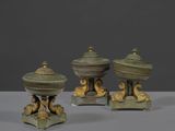 trois figurines d'oiseaux en bronze posées sur des socles, disposées sur une table