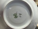 someone is holding a white plate with a green design on it