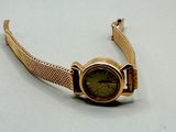 une montre-bracelet en or avec un cadran vert sur fond blanc