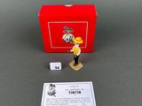 the small figurine is next to a red box and a card