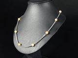 a black mannequin with a gold beaded necklace on it