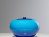 une image représentant un vase bleu posé sur une table blanche