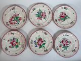 six assiettes ornées de motifs floraux posées sur une surface blanche