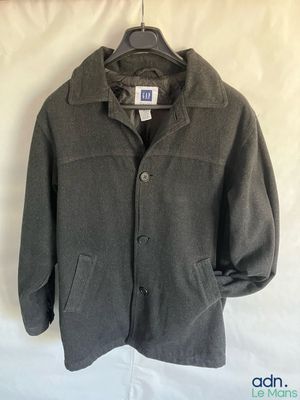 grey wool jacket hanging on a hanger on a white sheet