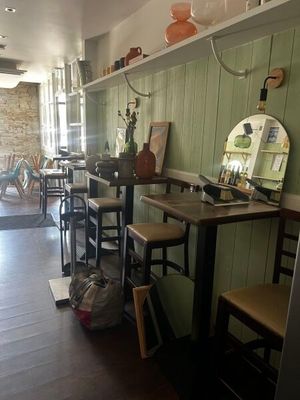 Dans un restaurant où un miroir est accroché au mur, des tables et des chaises sont alignées.
