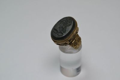 une image représentant une bague sur laquelle est posée une pièce de monnaie romaine