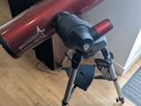 un télescope posé sur un trépied, sur un plancher en bois
