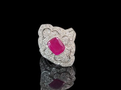 un gros plan d'une bague en pierre rose posée sur une surface noire