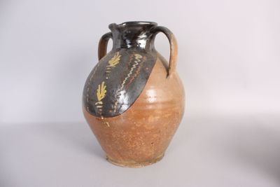 un vase marron et noir posé sur une table blanche