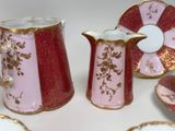 several pieces of pink and gold china sitting on top of a white table