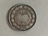 a silver coin with a wreath on it