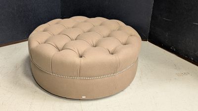 the large round ottoman is sitting on the floor in the corner of the room