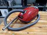 un aspirateur rouge posé sur une table en bois