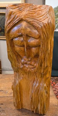 une sculpture en bois représentant un homme barbu, posée sur une table
