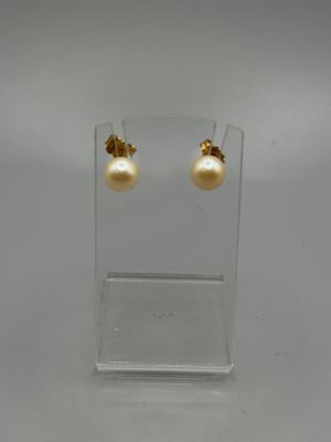 une paire de boucles d'oreilles en perles et en or, présentée dans un présentoir transparent