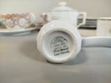 a white cup and saucer sitting on a table next to a plate