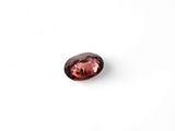 a close up of a red garnet stone on a white surface