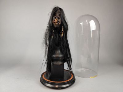 une statue représentant une femme aux longs cheveux noirs, placée sous un dôme de verre