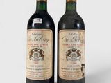 deux bouteilles de vin posées l'une à côté de l'autre sur une surface blanche