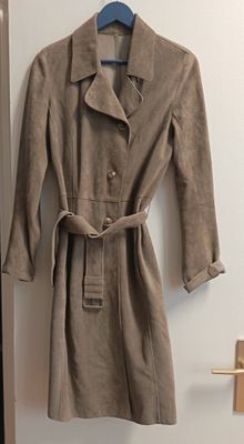 un trench-coat suspendu à un cintre devant une porte