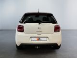 the rear end of a white car in a room with a white wall