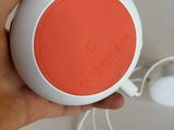 a person holding an orange and white speaker in their hand