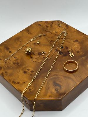 boîte à bijoux en bois avec des bagues et des chaînes dorées sur fond blanc