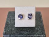 une paire de boucles d'oreilles en tanzanite posée sur un bloc de marbre