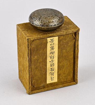 une petite boîte sur laquelle se trouve un objet en métal